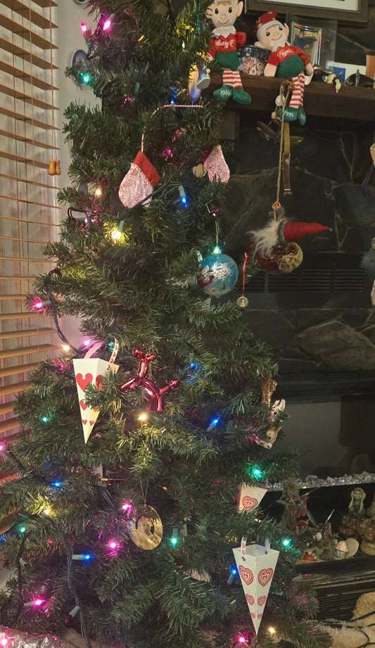 Christmas tree with colorful lights, heart-themed ornaments, and festive decorations in a living room