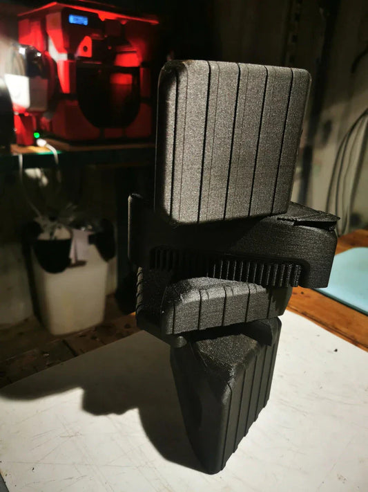 Stacked 3D-printed sidestep components with textured surface on a workbench, 3D printer in background