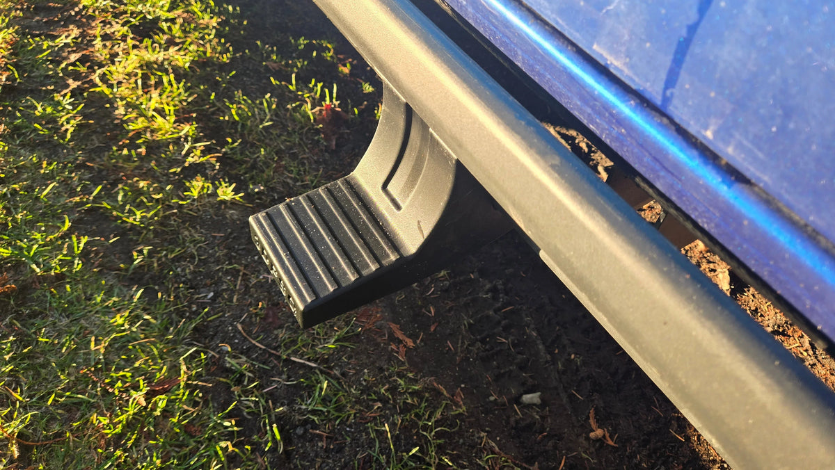 Closeup of a black snap-on sidestep attached to a blue vehicle in sunlight
