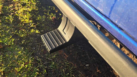 Closeup of a black snap-on sidestep attached to a blue vehicle in sunlight