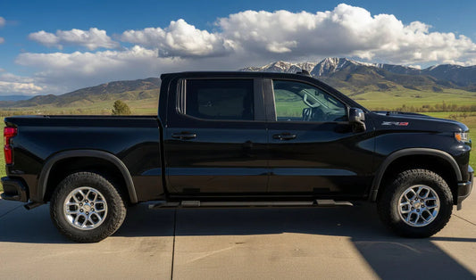 Black ZR2 pickup truck with snap-on sidesteps on a concrete driveway, mountains in background
