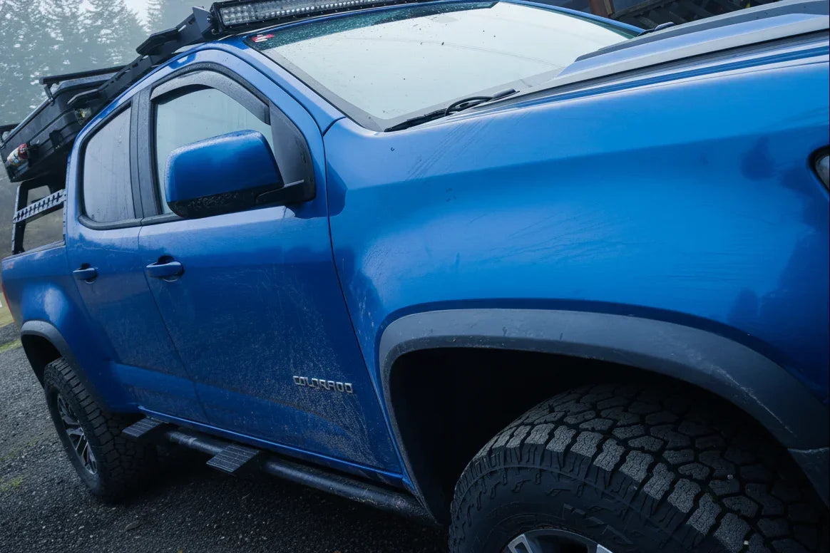 Blue pickup truck with tool-free snap-on sidesteps and off-road tires parked outdoors